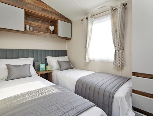 two beds in a small room with a window at Billing Aquadrome Holiday Park in Great Billing