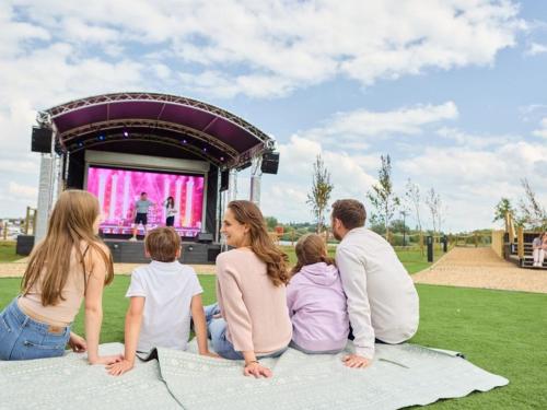 a group of people sitting on a blanket in front of a stage at Billing Aquadrome Holiday Park in Great Billing