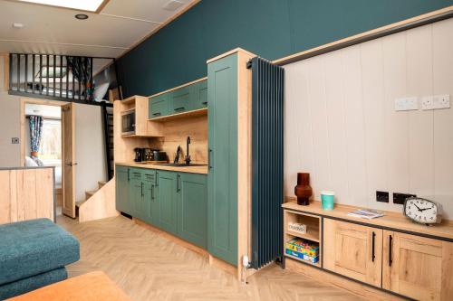 a kitchen with green cabinets and a blue wall at Billing Aquadrome Holiday Park in Great Billing