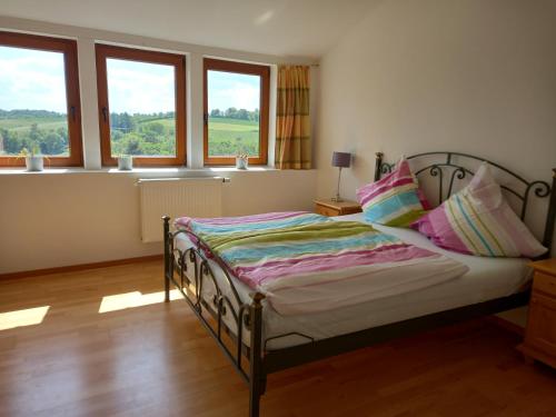 a bedroom with a bed with pillows and windows at Pension Espenhof 