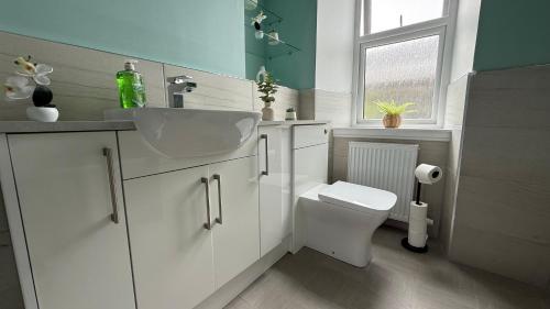 a bathroom with a sink and a toilet and a window at The Bakehouse - by Caithness Luxury Apartments NC500 - 5 Bedroom Luxury Holiday Home - Sleeps Work teams upto 5 & holiday makers upto 10 in Wick