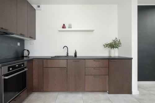 Una cocina con gabinetes de madera y un fregadero. en Modern Studio with Parking near Lake Malta by Noclegi Renters, en Poznan