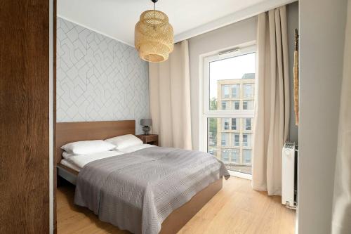 Un dormitorio con una cama y una ventana grande. en Modern Studio with Parking near Lake Malta by Noclegi Renters, en Poznan