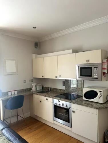 a kitchen with white cabinets and a blue chair in it at Crawford House- ScholarLee Living Apartments in Cork