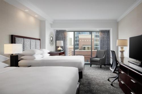 a hotel room with two beds and a television at Amway Grand Plaza Hotel, Curio Collection by Hilton in Grand Rapids