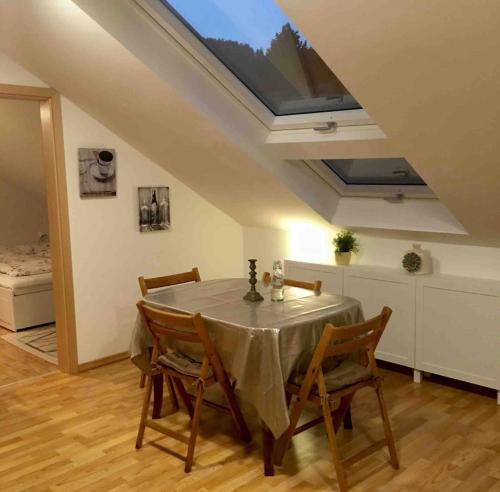 comedor con mesa con sillas y tragaluz en Elegante Ferienwohnung mit Kaminofen im Thüringer Wald, en Manebach