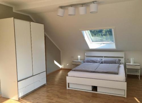 Una habitación blanca con una cama y una ventana en Elegante Ferienwohnung mit Kaminofen im Thüringer Wald, en Manebach