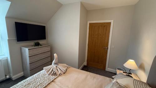 a bedroom with a bed and a flat screen tv at The Bakehouse - by Caithness Luxury Apartments NC500 - 5 Bedroom Luxury Holiday Home - Sleeps Work teams upto 5 & holiday makers upto 10 in Wick