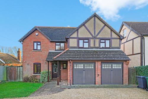 a red brick house with two garage doors at Detached 6 Bedroom Cambridgeshire Abode - Pets in Whittlesford
