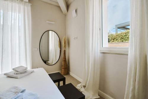 a bedroom with a bed and a mirror and a window at Villa in centro con Giardino e Parcheggio - La Casa della Giuliana in Santarcangelo di Romagna