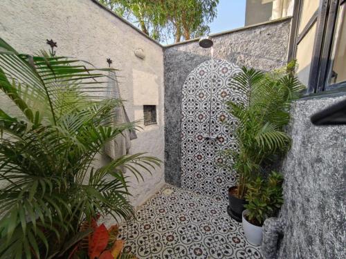 a tiled walkway with potted plants next to a building at SaffronStays Jade in Kārli