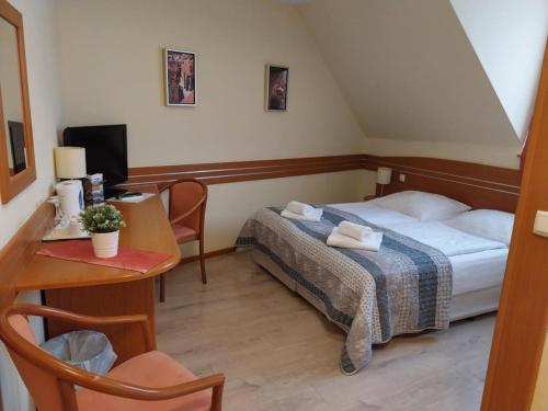 a hotel room with a bed and a table and a desk at Erhardt Panzió in Sopron