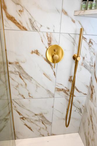 a shower with a gold shower head on a marble wall at Castle & Sea, Platanos Retreat in Agia Marina