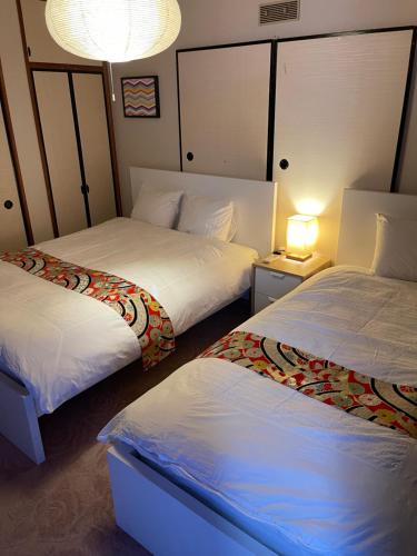 a hotel room with two beds and a lamp at Share House on the Hill in Yokohama