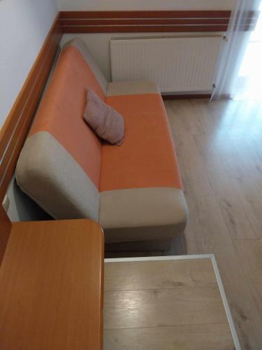 an orange couch with a pillow on it in a room at Erhardt Panzió in Sopron