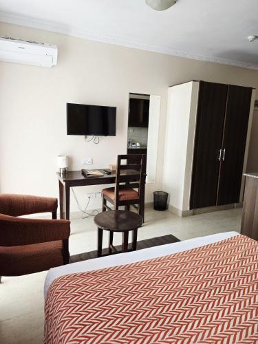 a bedroom with a desk and a chair and a bed at Vittoria Suites Milimani, Kisumu in Kisumu