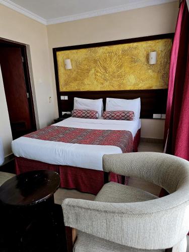 a hotel room with a bed and a chair at Vittoria Suites Milimani, Kisumu in Kisumu