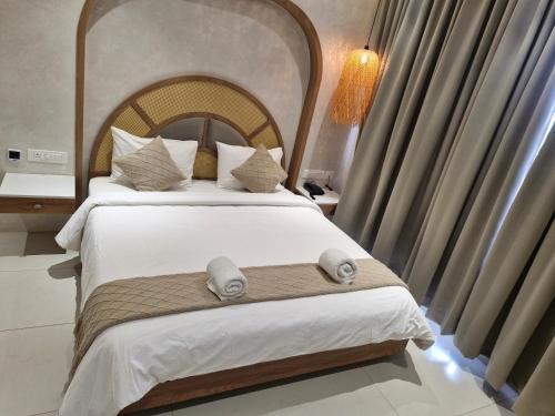 a bedroom with a large bed with a large headboard at Three Oceans Resort in Kanyakumari