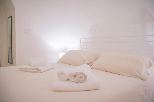 a white bed with towels and pillows on it at Ad un passo da Cisternino - Trulli con Camino, Foresta e BBQ in Cisternino