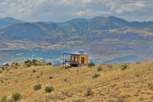 a small house on a hill with mountains in the background at Sareni in Areni