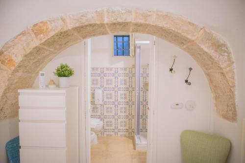 a bathroom with an archway with a toilet and a sink at Ad un passo da Cisternino - Trulli con Camino, Foresta e BBQ in Cisternino
