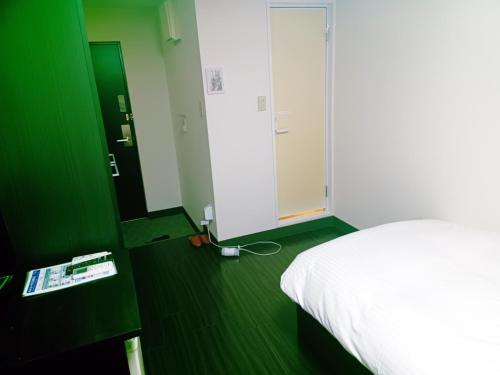a bedroom with a white bed and a green wall at Ace Inn Asakusa in Tokyo