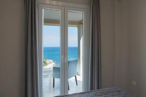 a bedroom with a glass door with a view of the ocean at Beachfront Villa Seasun by PosarelliVillas in Agios Spyridon Corfu