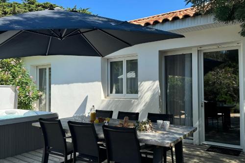 a table with an umbrella on a patio at Villa Californie - Domaine Le Sherwood in Notre-Dame-de-Monts