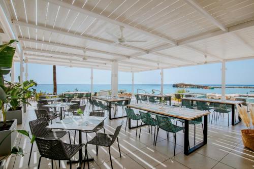 a restaurant with tables and chairs and the ocean at Nissi Beach Resort in Ayia Napa