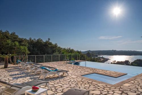 a pool with chairs and a view of the water at Beachfront Villa Seasun by PosarelliVillas in Agios Spyridon Corfu