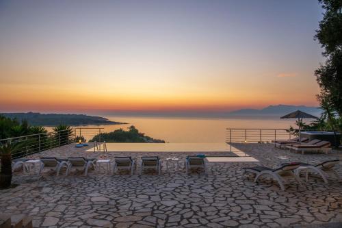 a group of tables and chairs in front of a lake at Beachfront Villa Seasun by PosarelliVillas in Agios Spyridon Corfu