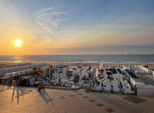 a beach with white buildings and the ocean at sunset at Appartement Knokke - 2 Chambres in Knokke-Heist