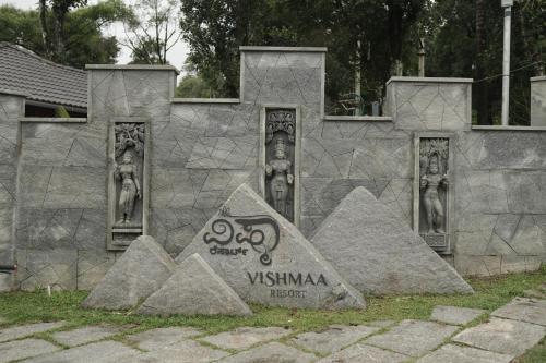 a monument in front of a stone wall at Vishmaa Resort in Madikeri