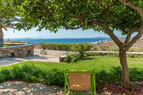 a green chair sitting in the grass under a tree at La Casa Tinos 22 in Agios Ioannis Tinos