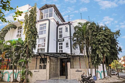 a white building with palm trees in front of it at Super Hotel O Vrindavan in Kolkata