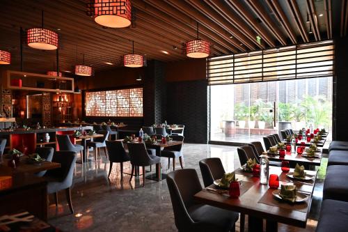 a dining room with tables and chairs in a restaurant at Holiday Inn New Delhi Mayur Vihar Noida by IHG in New Delhi