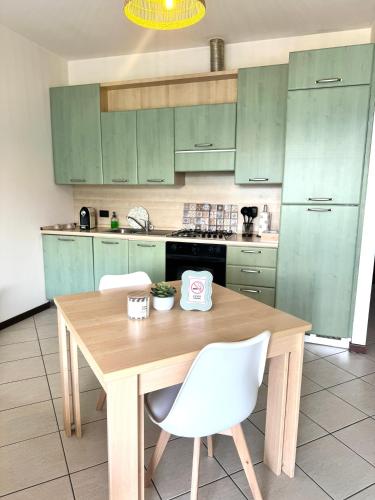 a kitchen with green cabinets and a wooden table and chairs at Casa Lagobello, Piscina e Relax sul Lago Maggiore in Germignaga