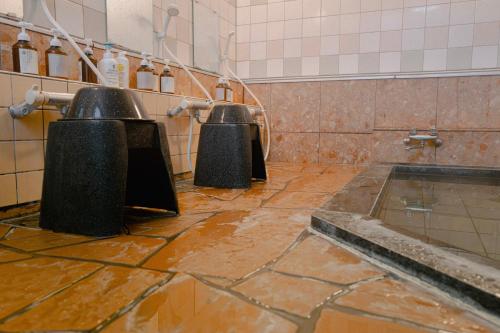 a dirty bathroom with two urinals and a tub at SLEEEP JP Myoko in Myoko