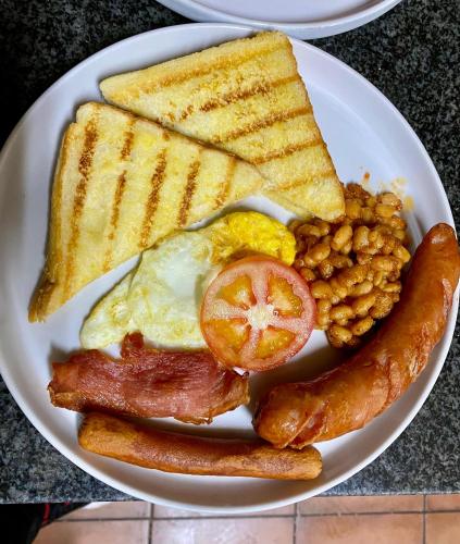 a plate of breakfast food with eggs bacon beans and toast at Gold Crown International Hotel With Complementary Breakfast and WiFi in Johannesburg
