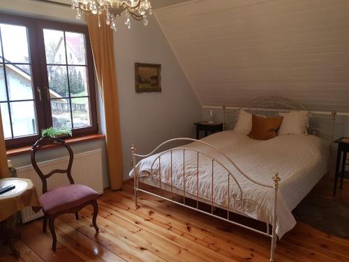 ein Schlafzimmer mit einem Bett und einem Stuhl und Fenstern in der Unterkunft Mikołajówka - przytulny dom z widokiem in Świeradów-Zdrój