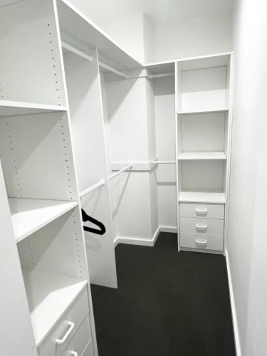 a white closet with white shelves and a black floor at Spacious Queen Room with Attached Bathroom - OR1 in Guildford