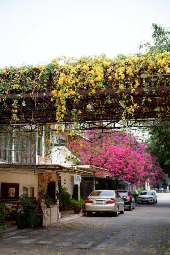 a pergola with flowers and cars parked on a street at Delio Boutique Hotel in Udon Thani
