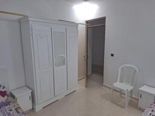 a bedroom with a white cabinet and a chair at منزل للكراء اليومي in Chefchaouene