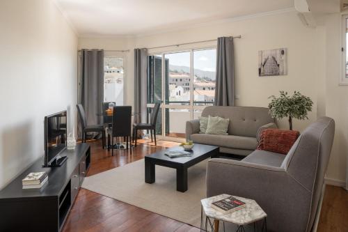 Una sala de estar con un sofá y un televisor. en Golden Star AU by An Island Apart, en Funchal