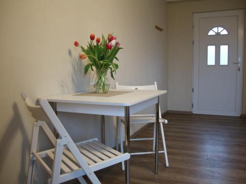 a vase of flowers sitting on a table with two chairs at Pension Bäumi-Hof in Seehausen