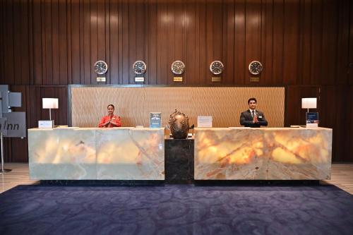two people sitting at tables in a room at Holiday Inn New Delhi Mayur Vihar Noida by IHG in New Delhi