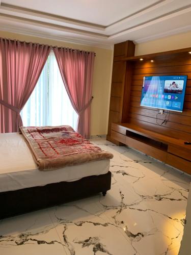 a bedroom with a bed and a flat screen tv at Red Onion Ayubia in Ayubia