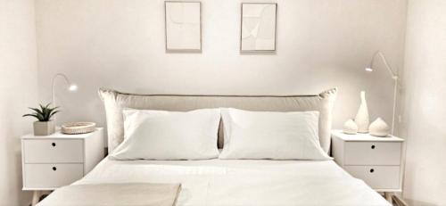 a white bedroom with a white bed with two night stands at SeaHouse by Jelena in Bibinje