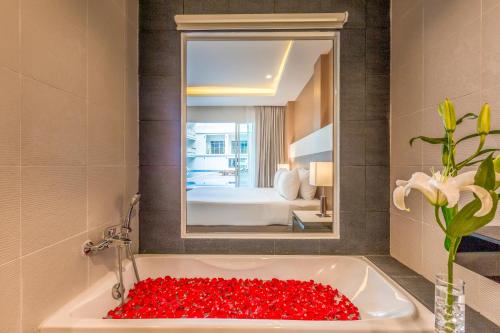 卡隆沙灘的住宿－Chanalai Hillside Resort, Karon Beach，一间设有装满红玫瑰的浴缸的浴室