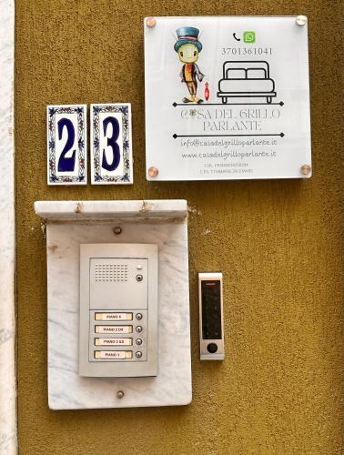 a sign on the side of a building with a pay phone at Casa Del Grillo Parlante in Aragona